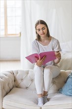 Portrait young woman reading book home