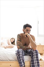 Sad young man sitting bed front his girlfriend