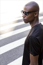 Serious young male athlete black shirt wearing sunglasses looking away