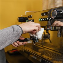Side view male barista cleaning professional coffee machine