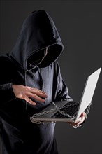 Side view male hacker with laptop protected by metal chain