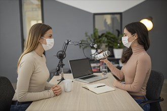 Side view women with medical masks broadcasting together radio