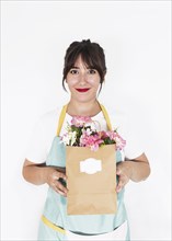 Smiling female florist holding paper bag full fresh flowers