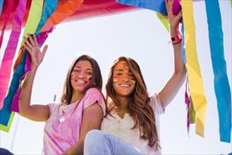 Smiling portrait young women with holi color their face looking camera