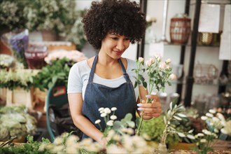 Smiling young female florist arranging flowers shop