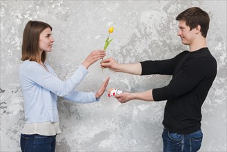 Woman accepting yellow tulip flower no cigarette packet offering by handsome man
