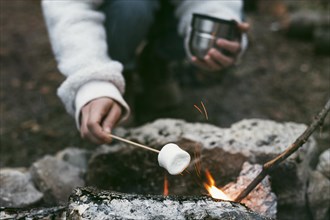 Woman burning marshmallows camp fire