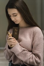 Woman praying with wooden cross bible