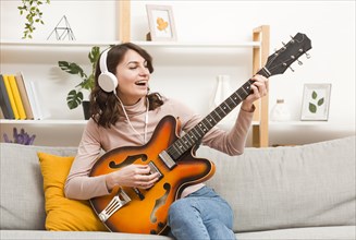 Woman with headphones playing guitar