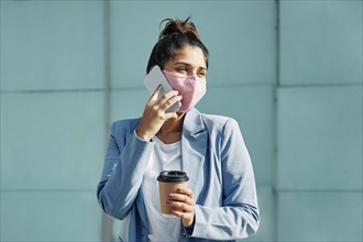 Woman with medical mask coffee talking smartphone airport during pandemic