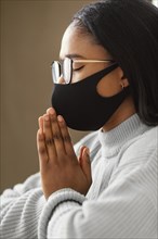 Young woman wearing face mask while praying