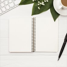 Blank spiral notepad with keyboard coffee cup pen white backdrop