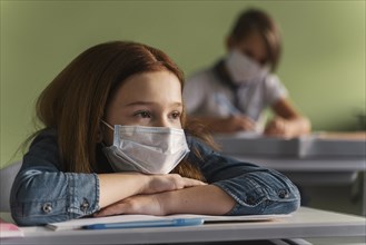 Children with medical masks listening teacher class