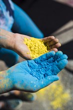 Close up two women s hand holding yellow blue holi color
