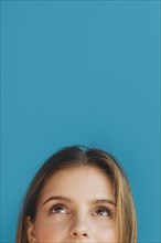 Close up young woman s face looking up against blue backdrop