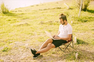 Concentrated hipster working with laptop outdoors