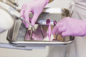 Dentist hand pink gloves arranging dental tools tray