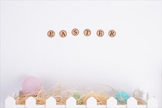 Easter word near bright eggs hay box