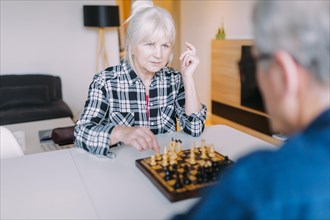 Elderly couple playing chess retirement home