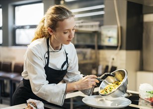 Female chef pouring food plate