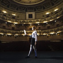 Female mime reading manuscript empty auditorium