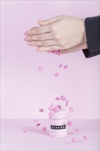Female s hand falling pink pills placebo bottle pink background