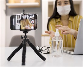 Female vlogger home with smartphone hand sanitizer
