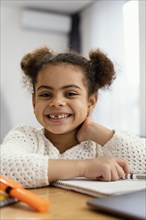 Front view happy little girl home during online school with laptop
