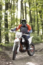 Front view stylish man riding motorbike forrest