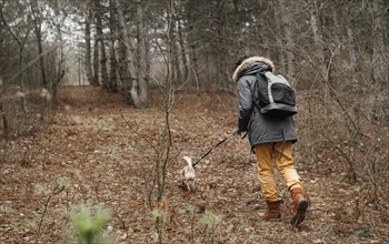Full shot traveler walking dog forest