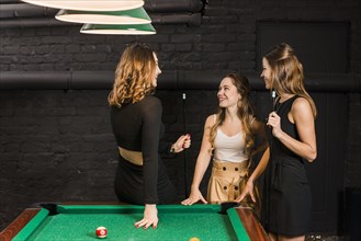 Group happy female friends standing near snooker table