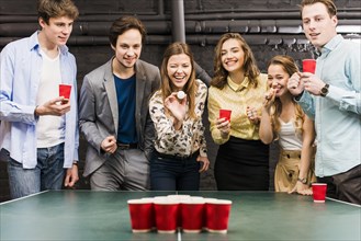 Group happy smiling friends enjoying beer pong game table bar