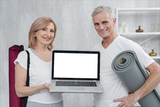 Happy couple holding yoga mat laptop with white screen home