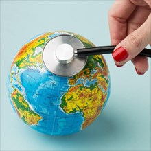 High angle hand consulting earth with stethoscope