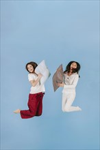 Laughing women jumping with pillows