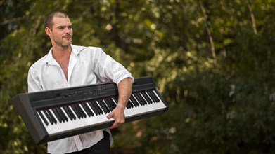 Man holding his digital piano outdoors