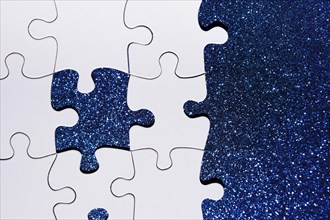 Overhead view puzzle piece blue glitter background