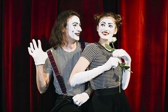Portrait two happy mime artist front red curtain