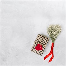 Present box with ornament paper heart near plant with ribbon