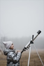 Side view little girl using telescope