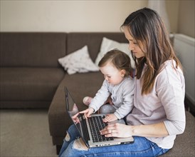 Side view mother with her child sitting sofa using laptop