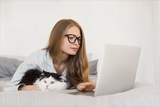 Side view woman working laptop from home pajamas with cat