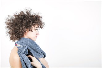 Side view young woman with curly hair wipes her body with towel against white background