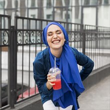 Smiley girl wearing hijab holding smoothie