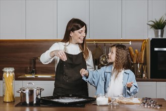Smiley mother daughter cooking together kitchen home