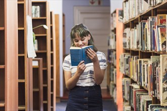 Smiling schoolgirl reading book library