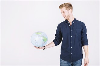 Smiling young man looking globe