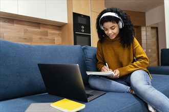 Teenage girl with laptop headphones during online school