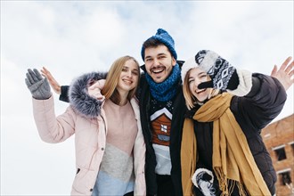 Three friends winter clothes waving with hands outside