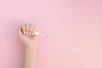 Top view hand holding tampon pink background